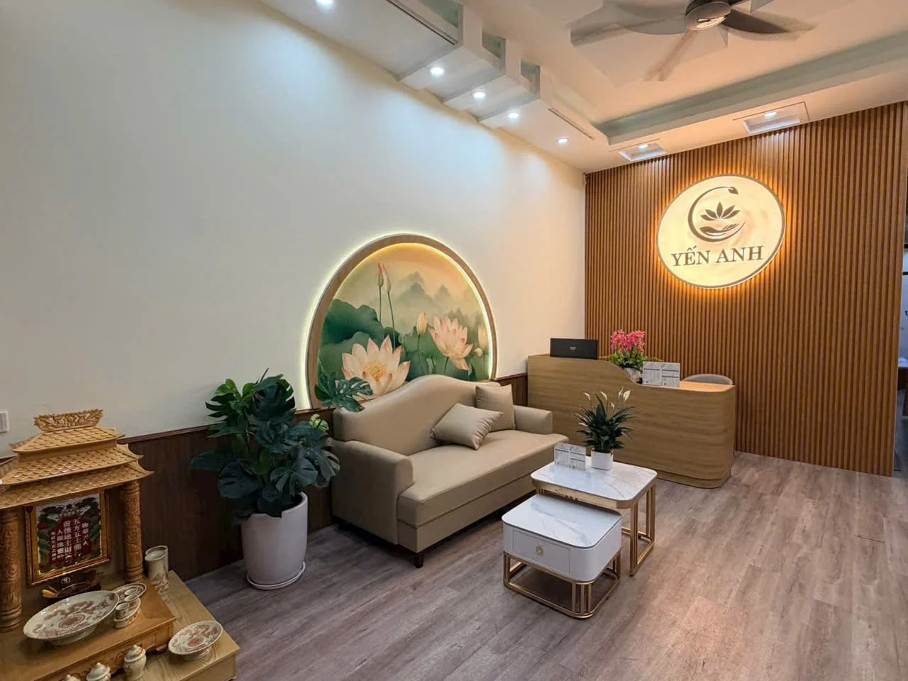 Không gian lễ tân thực tế tại Yến Anh với ghế sofa, tranh sen và logo trung tâm